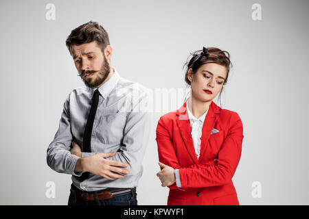 Il triste business l uomo e la donna in conflitto tra loro su uno sfondo grigio Foto Stock