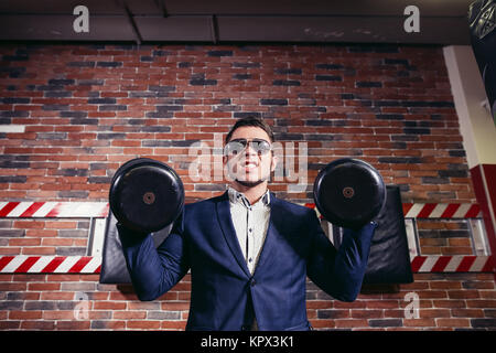 Imprenditore facendo dumbbell bicipite indossare tuta formale. Foto Stock