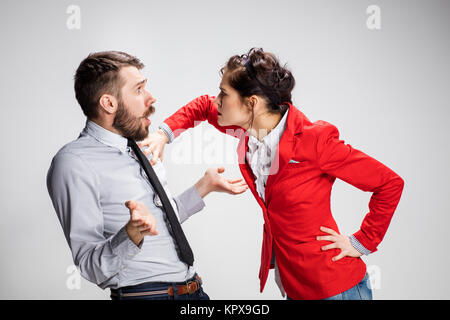 L'arrabbiato business l uomo e la donna in conflitto tra loro su uno sfondo grigio Foto Stock