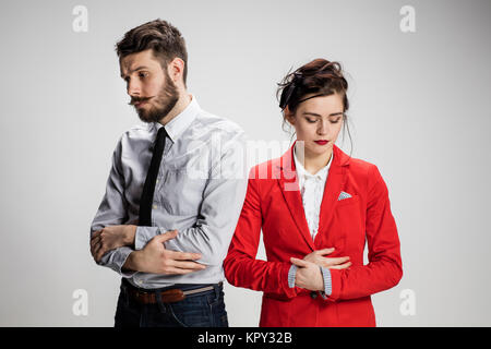 Il triste business l uomo e la donna in conflitto tra loro su uno sfondo grigio Foto Stock