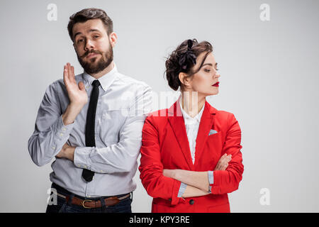 Il triste business l uomo e la donna in conflitto tra loro su uno sfondo grigio Foto Stock