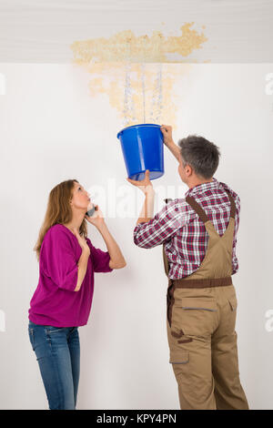 Lavoratore a raccogliere acqua nel secchio dal soffitto Foto Stock