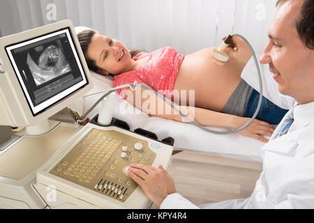 Medico lo spostamento del trasduttore a ultrasuoni sulla donna incinta il ventre Foto Stock