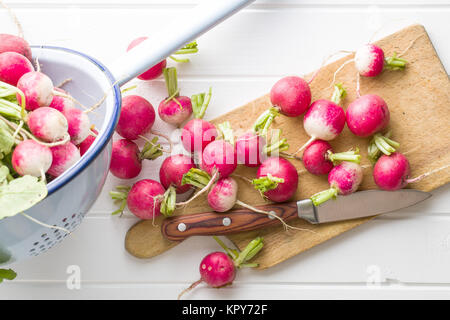 Ravanelli freschi sul vecchio tagliere. Foto Stock