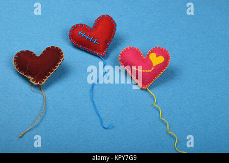 Tre feltro craft art cuori con filettature su blu Foto Stock