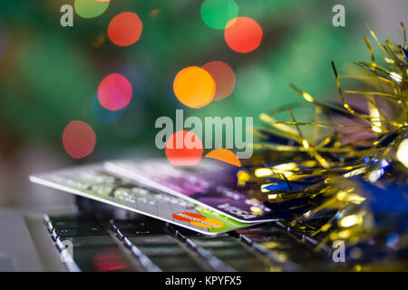 Concetto di immagine della spesa a Natale con le carte di credito/debito sulla tastiera di un computer.albero di Natale luci in background Foto Stock