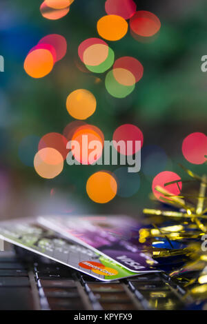 Concetto di immagine della spesa a Natale con le carte di credito/debito sulla tastiera di un computer.albero di Natale luci in background Foto Stock