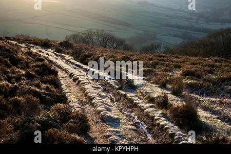 Frosty sentiero nelle colline sopra Hayfield nel Peak District. Bright sole mattutino. Foto Stock