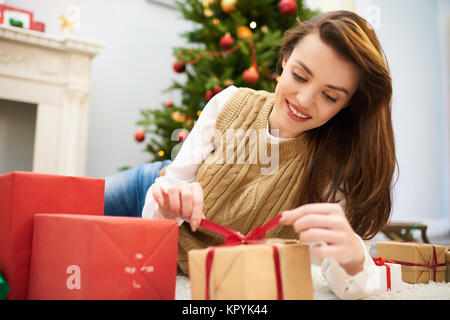 Curioso donna scartare un regalo di Natale Box Foto Stock