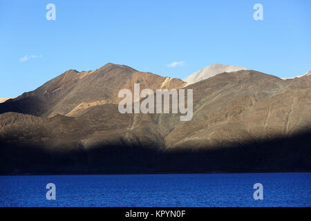 Ombra di picchi a paesaggio arido e le montagne himalayane dall'azzurro del lago di Pangong Tso, Ladakh, Jammu e Kashmir in India. Foto Stock