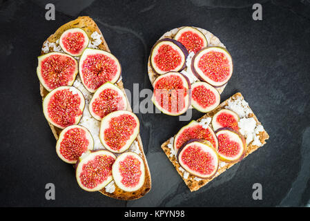 Vari snack sani dalla torta di riso, segale integrale fette biscottate cracker e pane di pasta acida pane tostato insieme con le figure e la ricotta su sla scuro Foto Stock