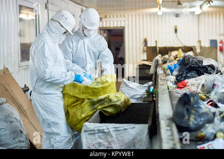 Lavoratori ordinamento di materiali riciclabili in impianto di trattamento dei rifiuti Foto Stock