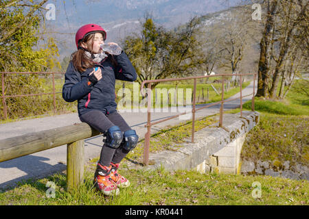 Preteen con pattino a rotelle casco, bere un acqua Foto Stock