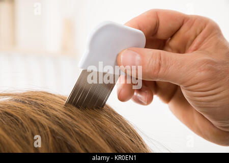 Persona che utilizza i pidocchi pettine su paziente i capelli Foto Stock