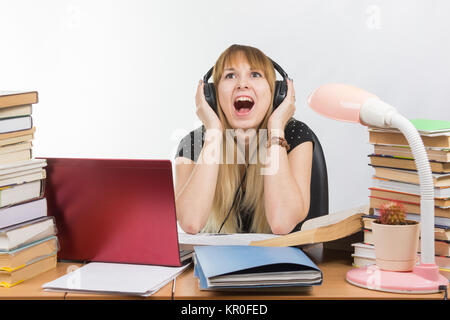 Uno studente grida dalla fatica durante l'ascolto di musica con le cuffie Foto Stock