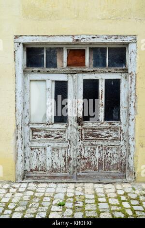 Grande cancello in legno con due ali e il vetro rotto in un vecchio e abbandonati edifici vuoti Foto Stock