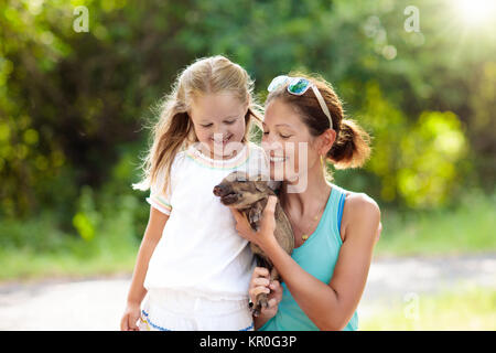 Bambini a giocare con gli animali della fattoria. Bambino alimentazione di animale domestico. Giovane madre e bambina tenendo il cinghiale baby al giardino zoologico. Kid giocando con newbo Foto Stock