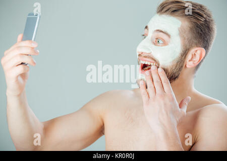 Giovane e bella uomo con maschera purificante sul suo volto facendo selfie Foto Stock