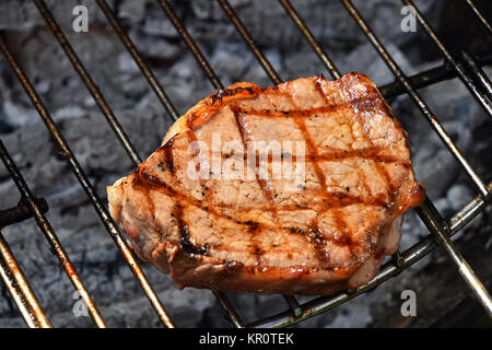 Una bistecca di carne cotti pronti sulla griglia Foto Stock