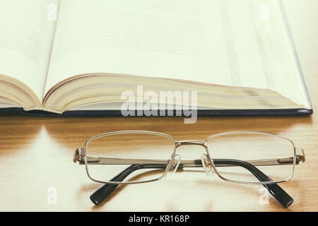 Chiudere i bicchieri e un libro sulla scrivania , stile vintage Foto Stock