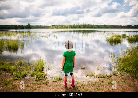 Ragazza in piedi sul bordo di un lago Foto Stock