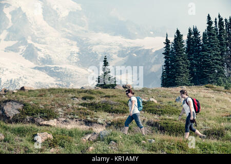 Due donne camminano lungo un sentiero alpino, Mt Rainier, Washington, Stati Uniti Foto Stock