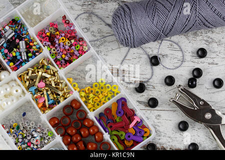 Scatola con accessori per l'artigianato e ricamo, in uno sfondo di legno Foto Stock