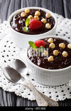 Deliziosi dessert: budino di cioccolato con nocciole, menta e lamponi vicino sul piano verticale. Foto Stock