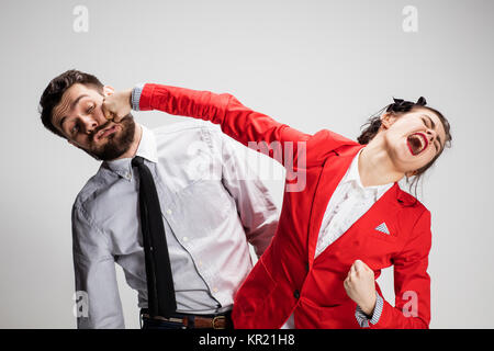 L'arrabbiato business l uomo e la donna in conflitto tra loro su uno sfondo grigio Foto Stock