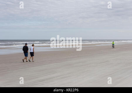 Giovane camminare e uomo sulla bicicletta su un Volusia County Beach,Florida USA Foto Stock