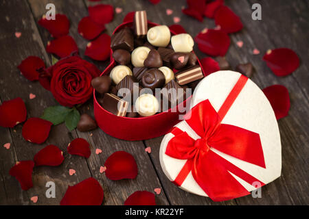 Rose rosse e praline di cioccolato in rosso a forma di cuore scatola regalo sfondo Foto Stock