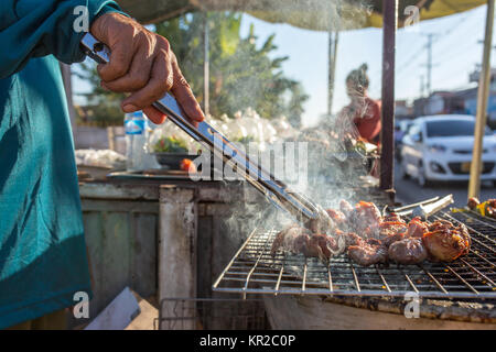 Lao venditore ambulante friggere la carne sulla griglia in Vientian, Laos Foto Stock