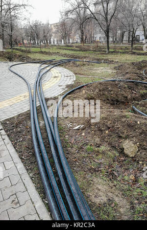 Posa del sistema di sprinkler della pipeline nel terreno trincee per la metropolitana del sistema di irrigazione, sistema di irrigazione, terra comunale lavora nel tardo autunno nel parco Foto Stock