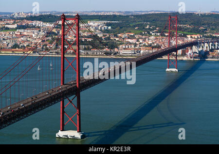 Il XXV Aprile Bridge (Ponte 25 de Abril) attraverso il Tago (TEJO) river, Lisbona, Portogallo con un panorama della città sullo sfondo. Foto Stock