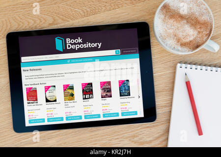 Il Book Depository sito su un iPad dispositivo tablet pc che si appoggia su una tavola di legno accanto a un blocco note e matita e una tazza di caffè (editoriale solo) Foto Stock