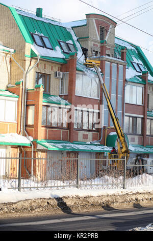 Il servizio di pulizia pulisce la neve dal tetto della casa. Foto Stock