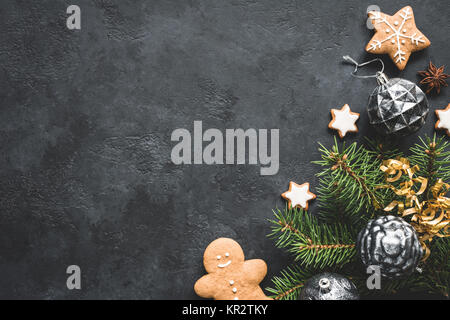 Elegante sfondo di Natale con vintage toys, abete e cookie su pietra nera dello sfondo. Vista superiore, copia spazio per il testo. Foto Stock