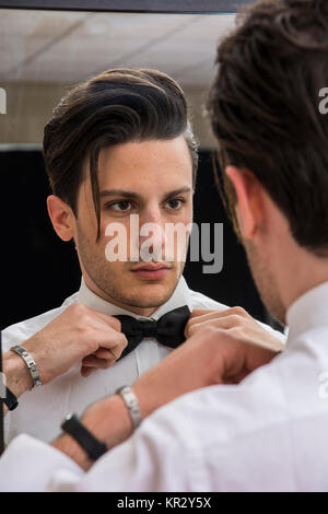 Close-up di uomo bello a bow tie-guardando lo specchio Foto Stock