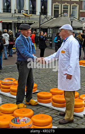 Un agricoltore, a sinistra e a un commerciante di formaggio, destra, contrattano il prezzo del formaggio Gouda presso il mercato del formaggio, Gouda, Paesi Bassi Foto Stock