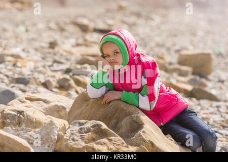 Ragazza annoiato a mare nella offseason stabilisce su una grande roccia Foto Stock