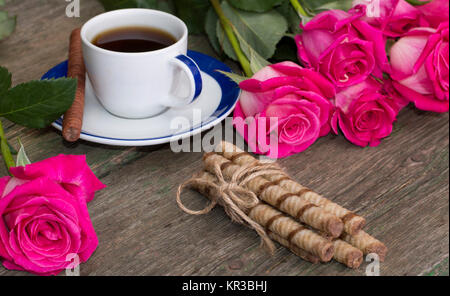 Ancora vita bouquet di rose, una tazza di caffè nero, il collegamento di cookie e di una rosa Foto Stock