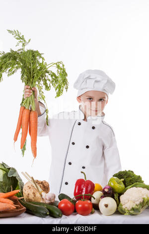 Un ragazzino come chef di cucina rendendo insalata, cucinare con le verdure. Isolato su bianco. Foto Stock