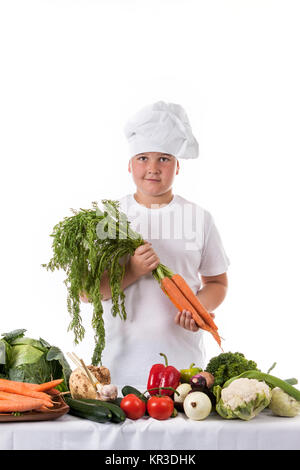 Un ragazzino come chef di cucina rendendo insalata, cucinare con verdura Foto Stock