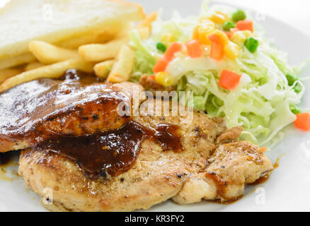 Carne di maiale alla griglia di filetto di manzo con insalata e patatine fritte sulla piastra bianca Foto Stock