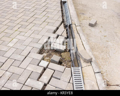 La distruzione del passaggio pedonale di pavimentazione con il drenaggio e la strada concreta Foto Stock