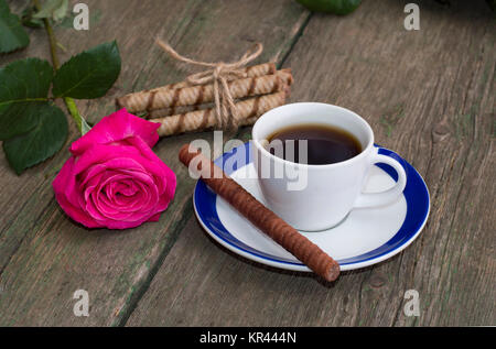 Tazza di caffè, uno rose, il collegamento dei cookie su una tavola di legno, una vita ancora Foto Stock