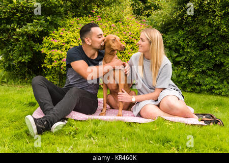 Matura sul tappeto con uomo baciare cane Foto Stock