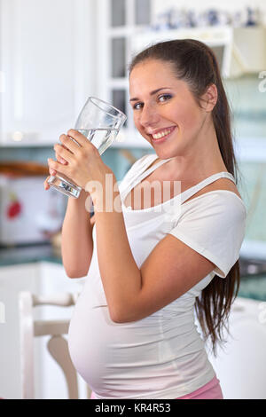 Donna incinta con un bicchiere di acqua. Foto Stock