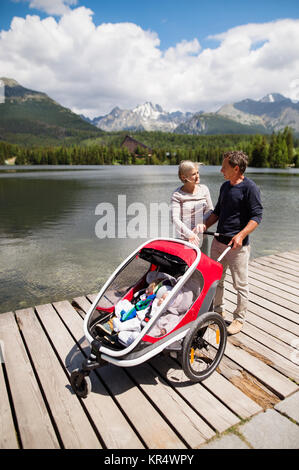 Coppia senior con i nipoti in jogging passeggino. Foto Stock