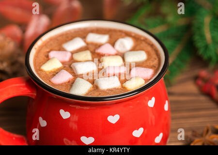 Tazza di cioccolata calda con caramelle marshmallow su sfondo di legno decorato di Natale il ramo di un albero da vicino Foto Stock